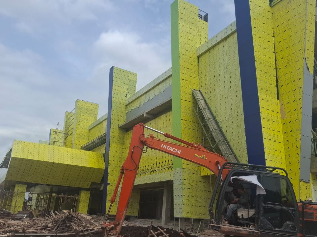 Gedung dengan fasad ACP kuning dalam proses pengerjaan